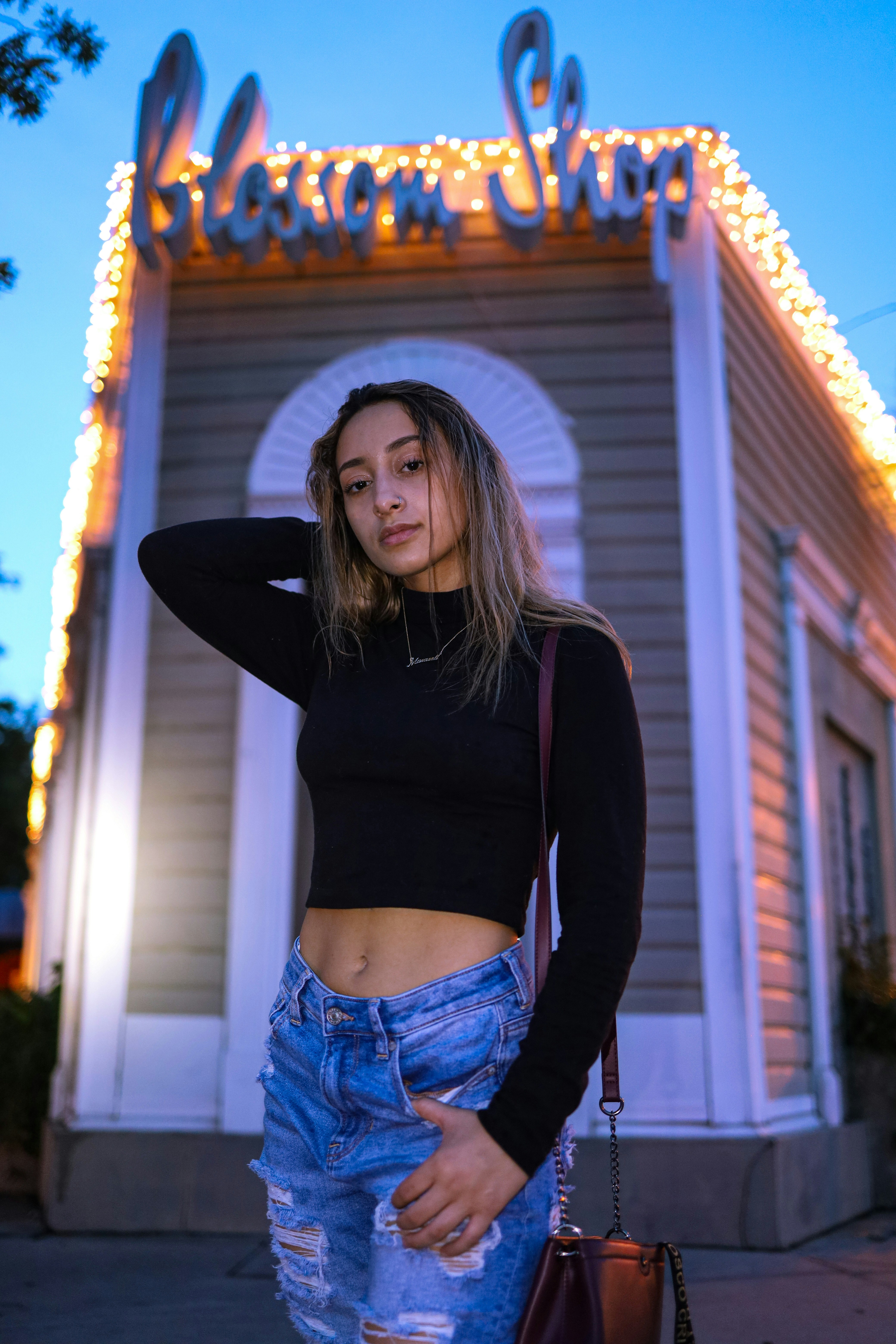 woman in black long sleeve shirt and blue denim shorts standing near white and brown building