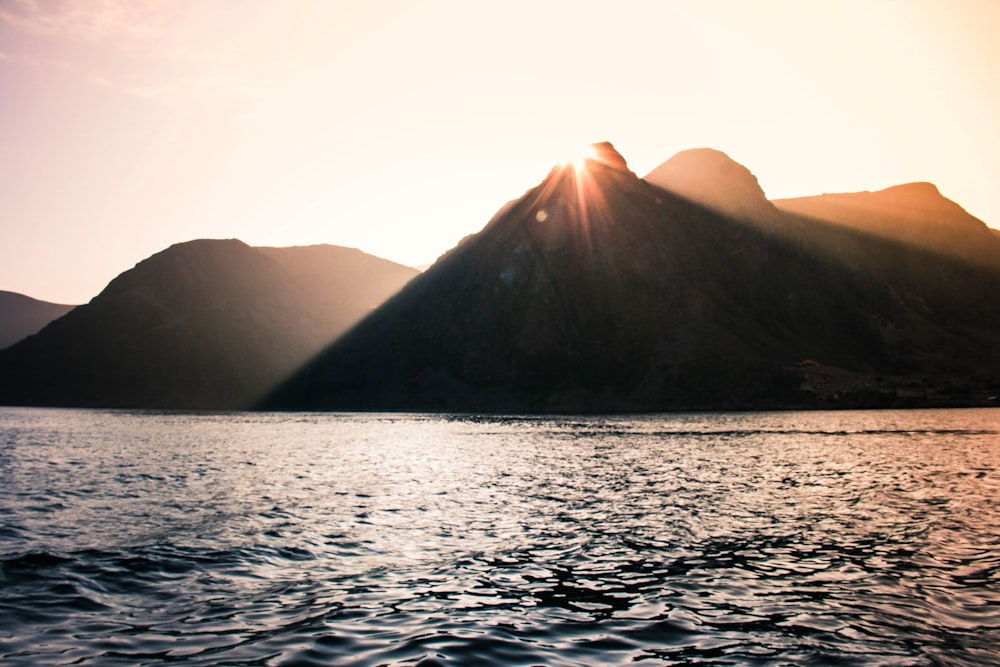 body of water near mountain during daytime