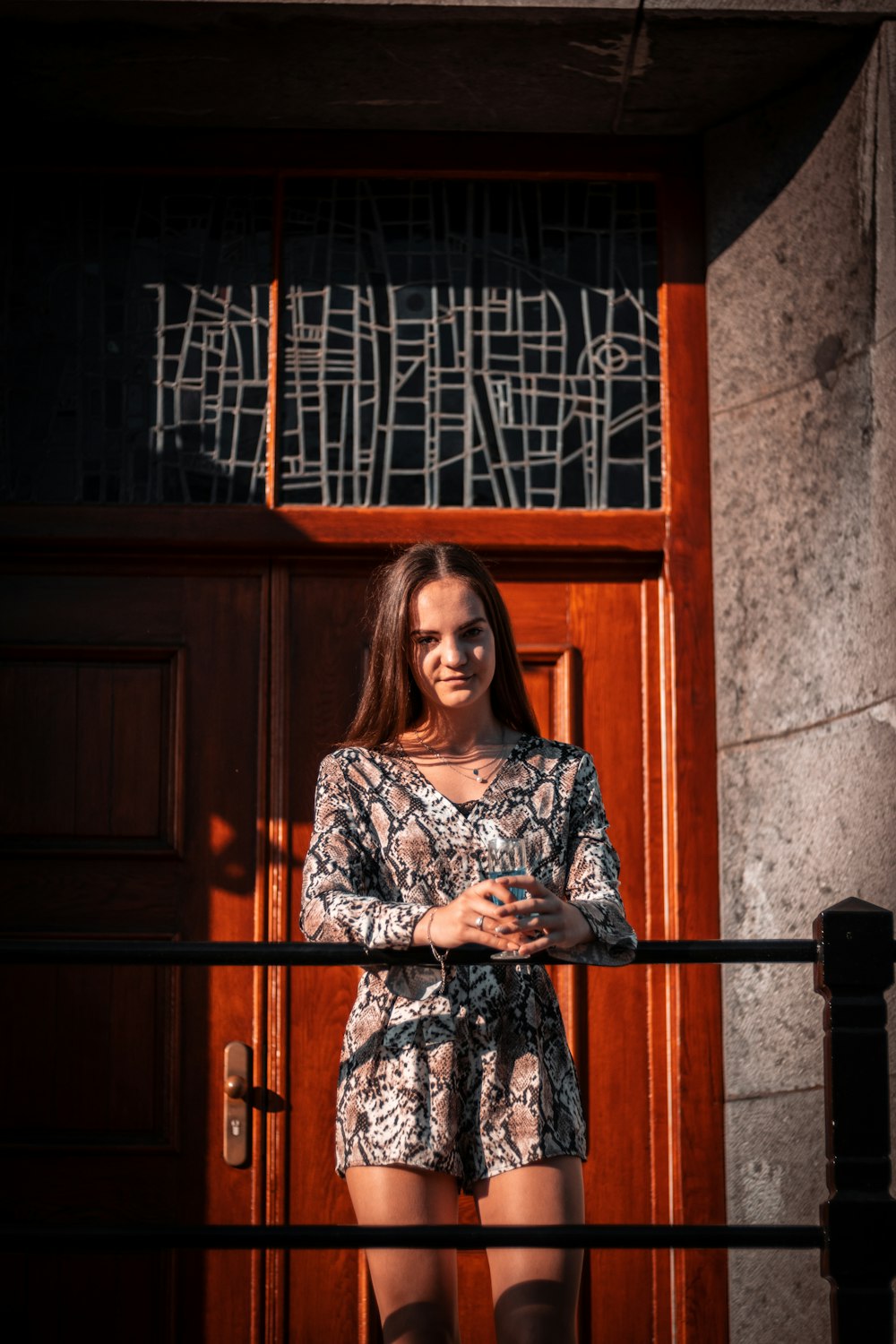 woman in black and white long sleeve dress standing beside brown wooden door