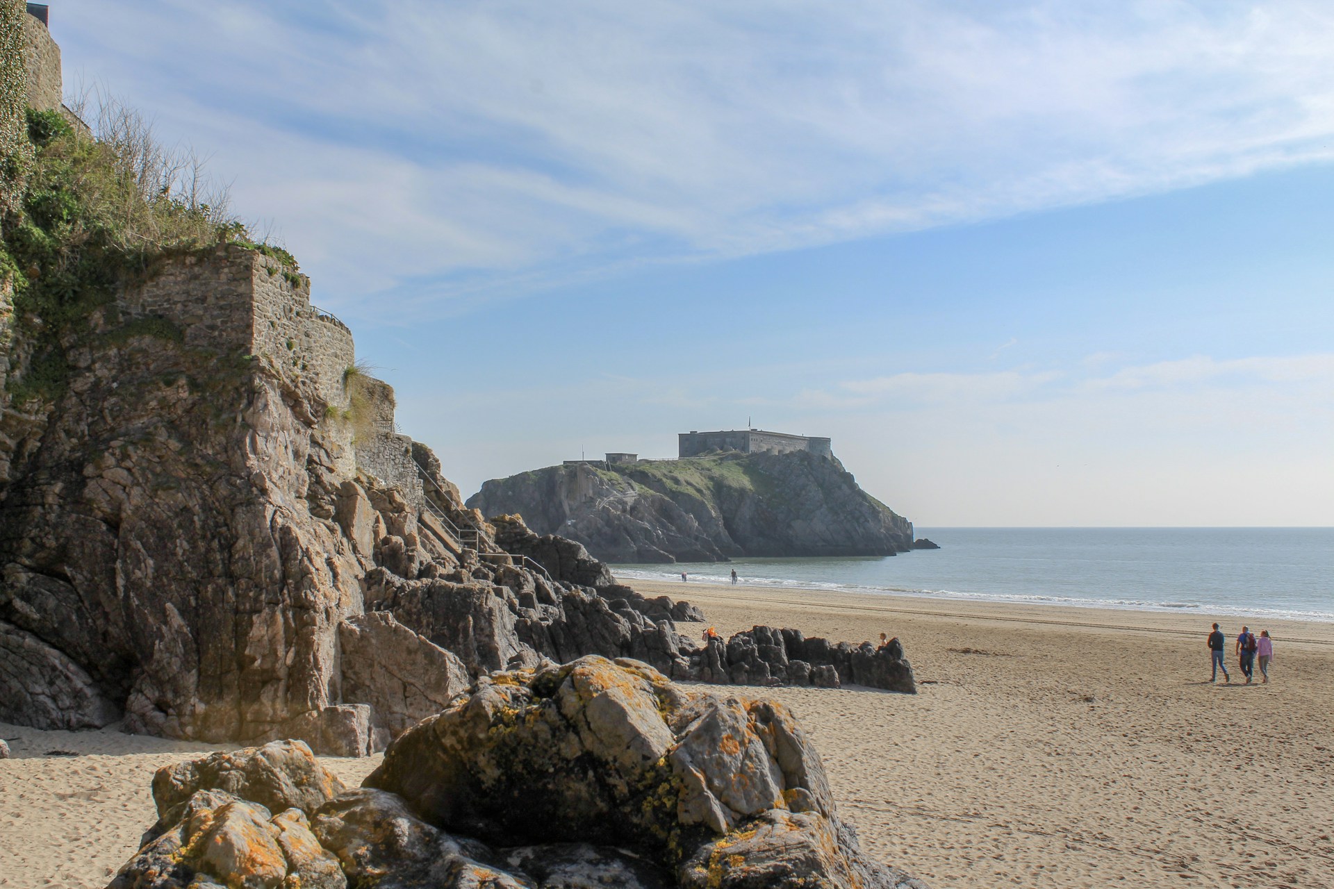 brown rocky mountain beside sea under blue sky during daytime
