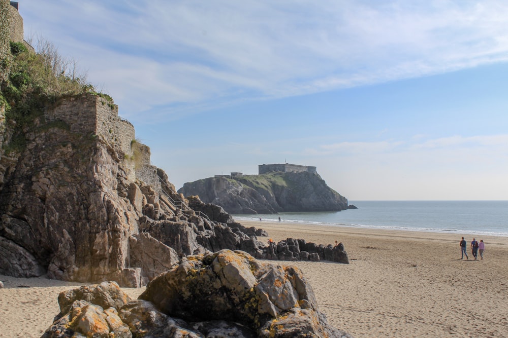 brown rocky mountain beside sea under blue sky during daytime