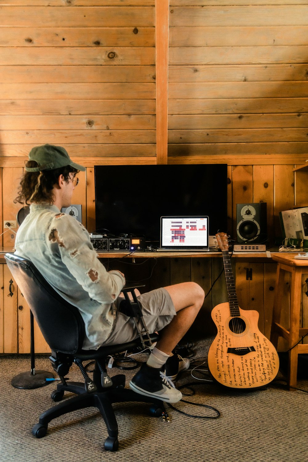 man in white dress shirt sitting on black chair playing guitar