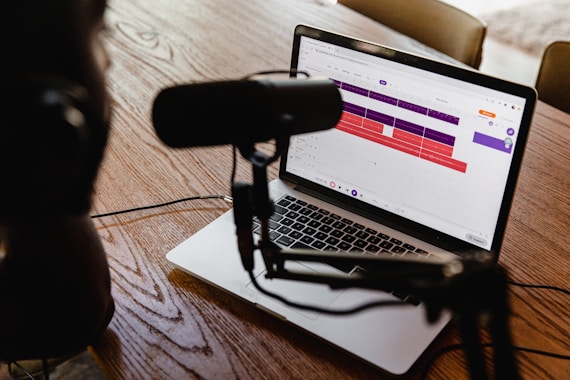 microphone in front of macbook pro on brown wooden table