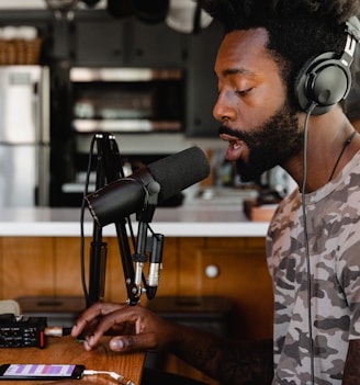 man in green and beige camouflage shirt sitting in front of microphone