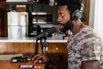 man in green and beige camouflage shirt sitting in front of microphone
