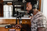 man in green and beige camouflage shirt sitting in front of microphone