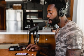 man in green and beige camouflage shirt sitting in front of microphone