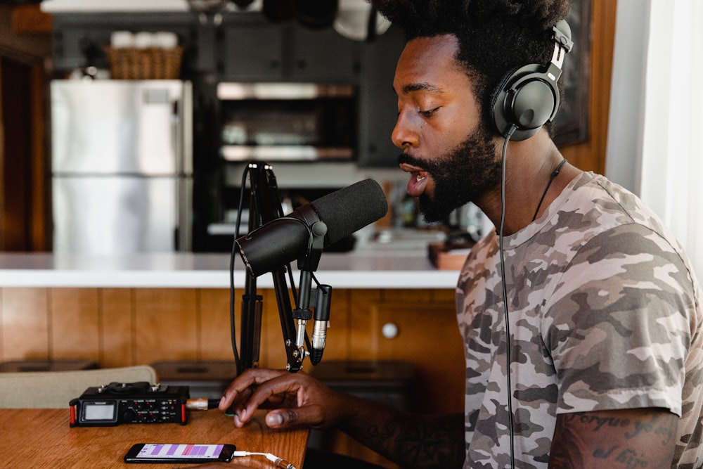 man in green and beige camouflage shirt sitting in front of microphone