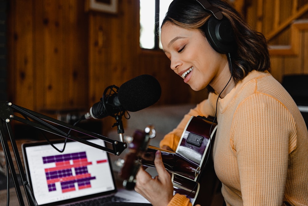 Woman playing guitar and recording copyright free background music for youtube.