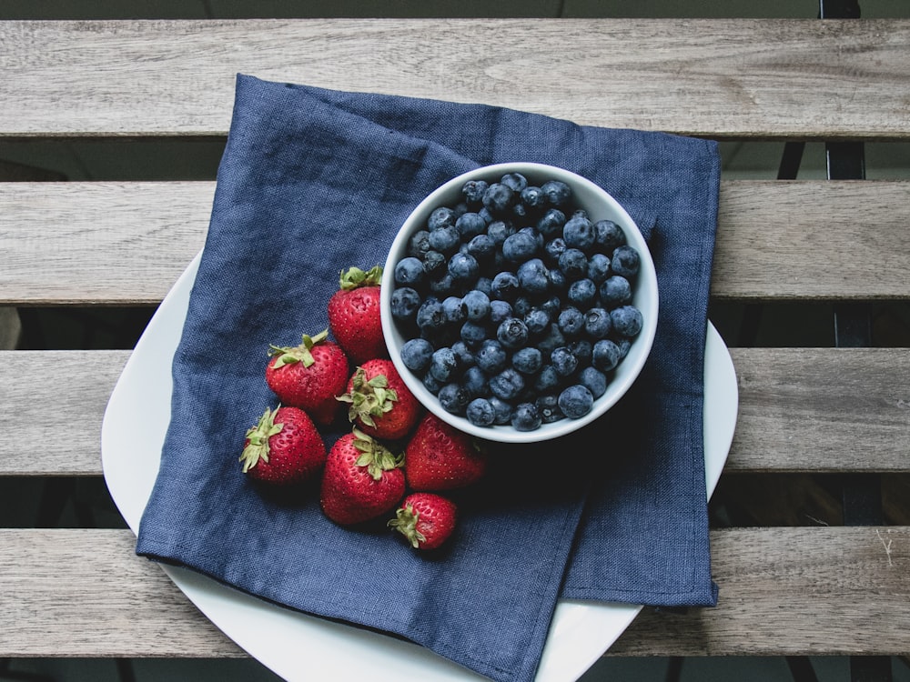 red strawberries on blue ceramic bowl