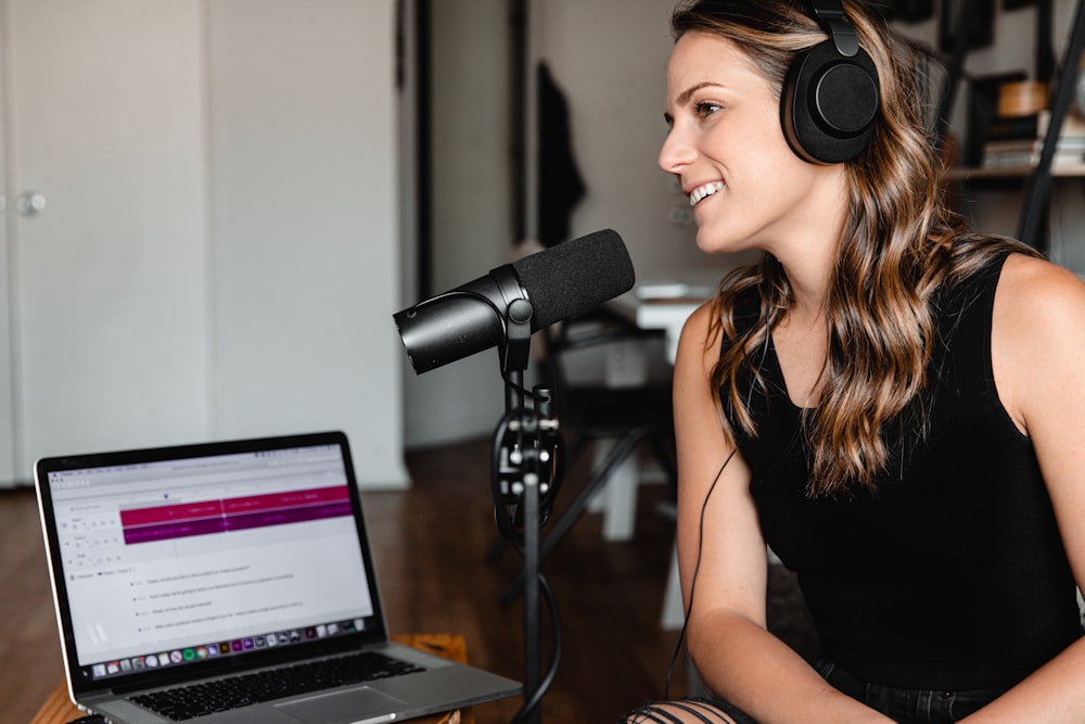 woman in black tank top sitting on chair in front of microphone