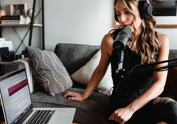 woman in black tank top sitting on couch using macbook