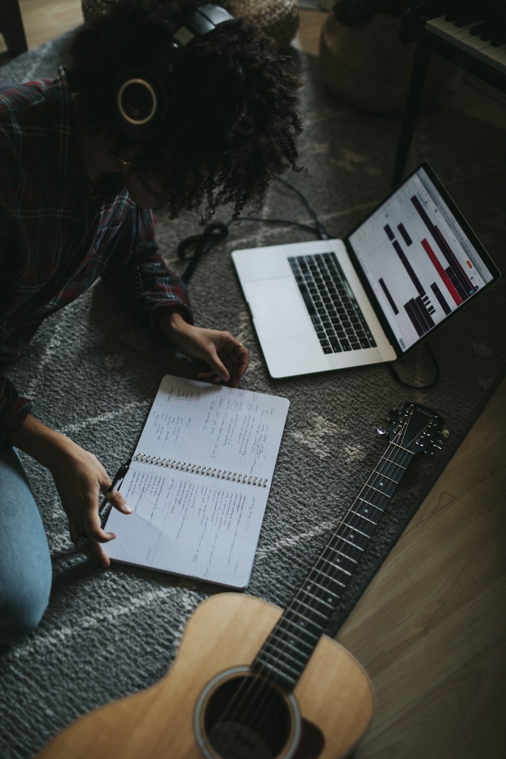 person in black jacket sitting on floor while writing on notebook