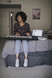 A joyful student playing piano during an interactive online lesson.
