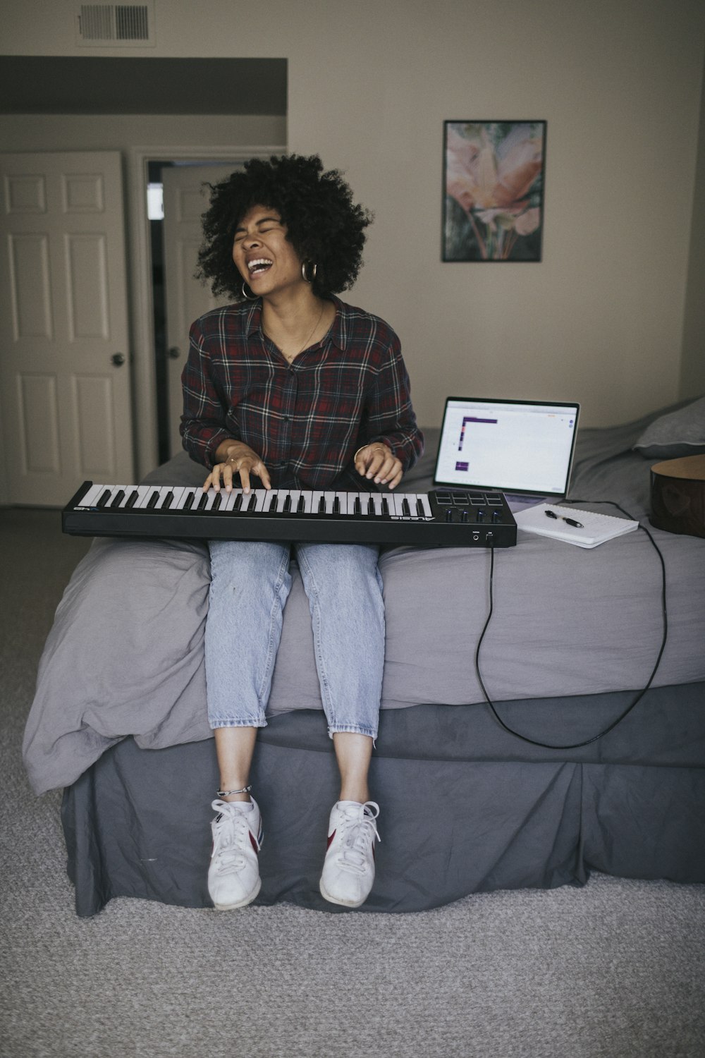 woman in red and black plaid dress shirt and blue denim jeans sitting on bed