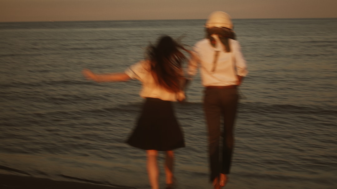 man and woman standing on beach during daytime