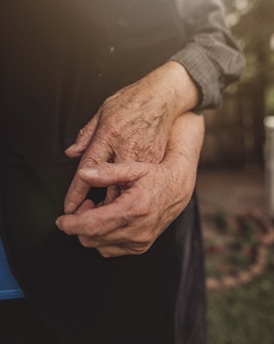 A compassionate caregiver holding hands with an elderly person.