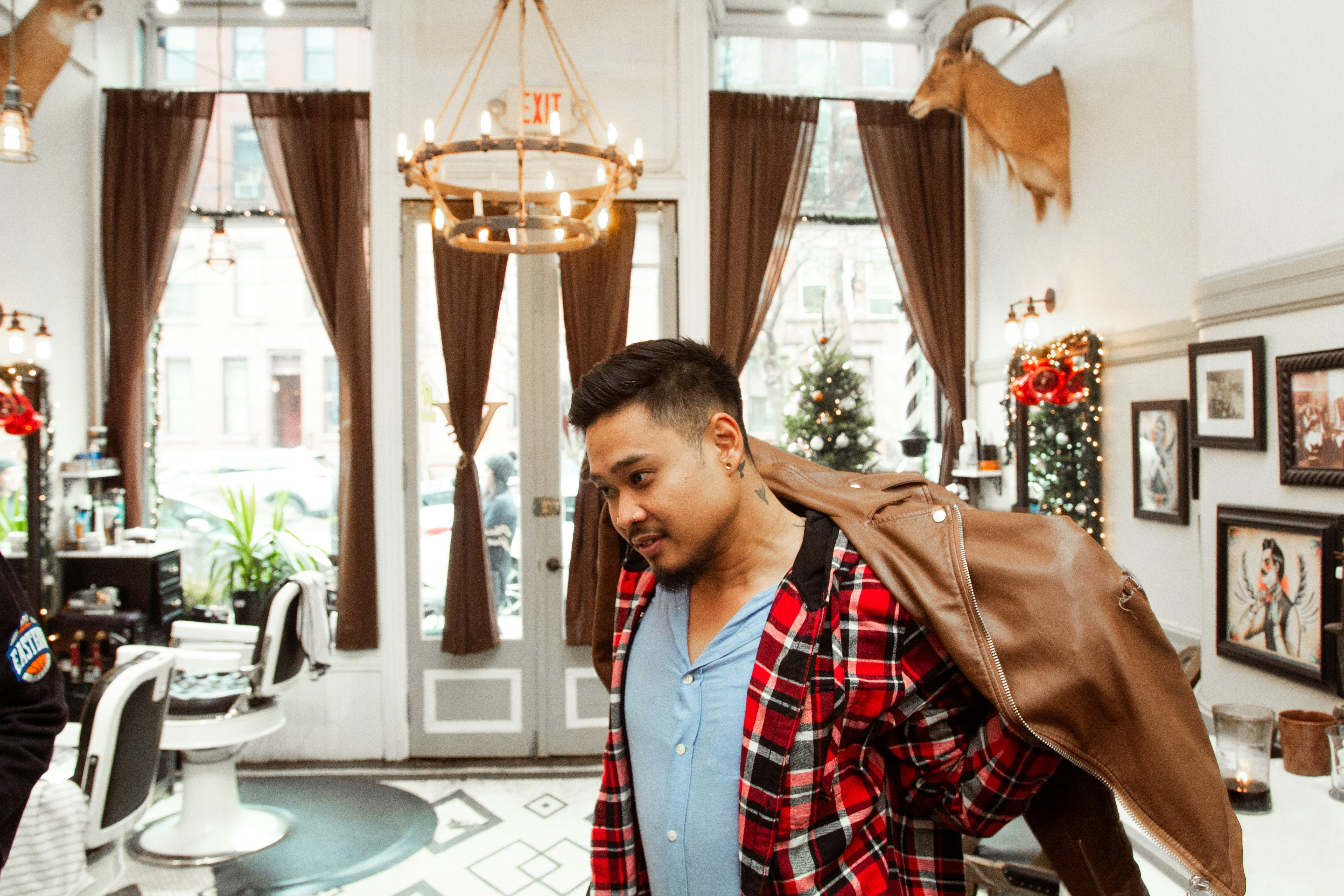 man in red black and white plaid dress shirt holding brown leather jacket new jersey teams background