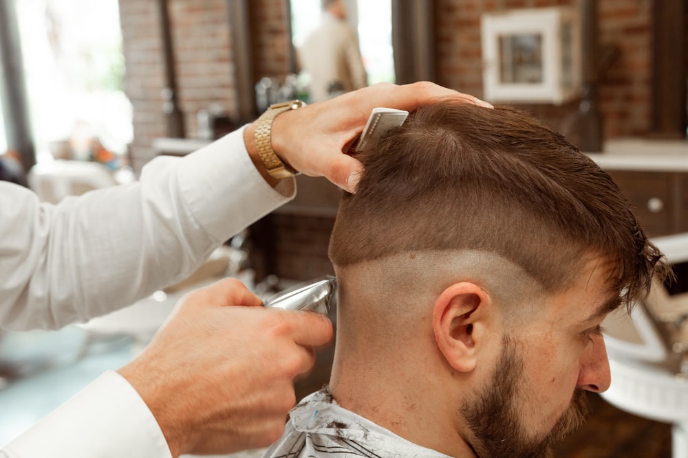 hombre en camisa de vestir blanca cortando el cabello del hombre