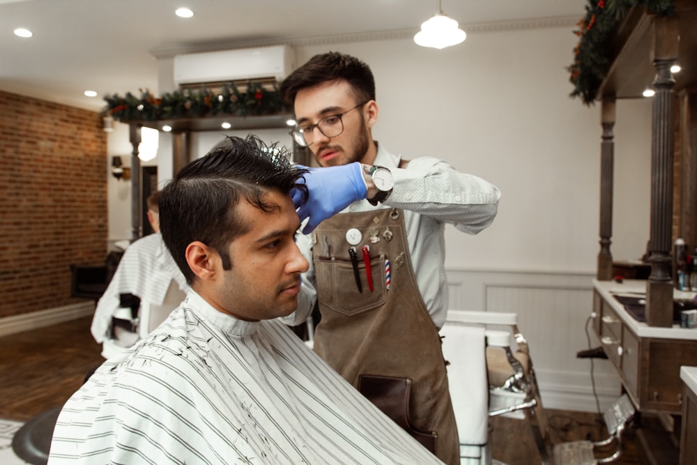 man in brown long sleeve shirt cutting hair of man