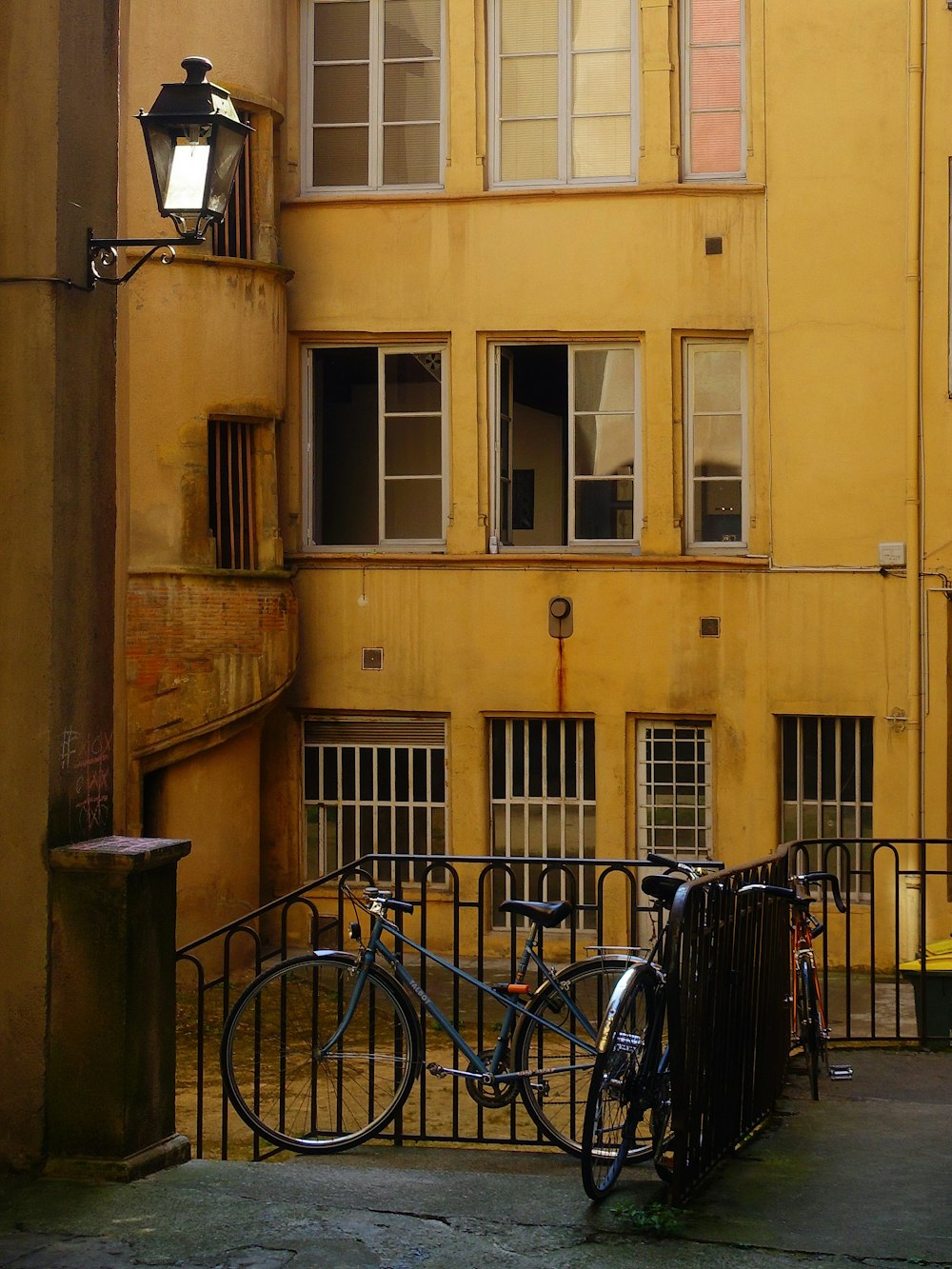 blue city bike parked beside yellow concrete building