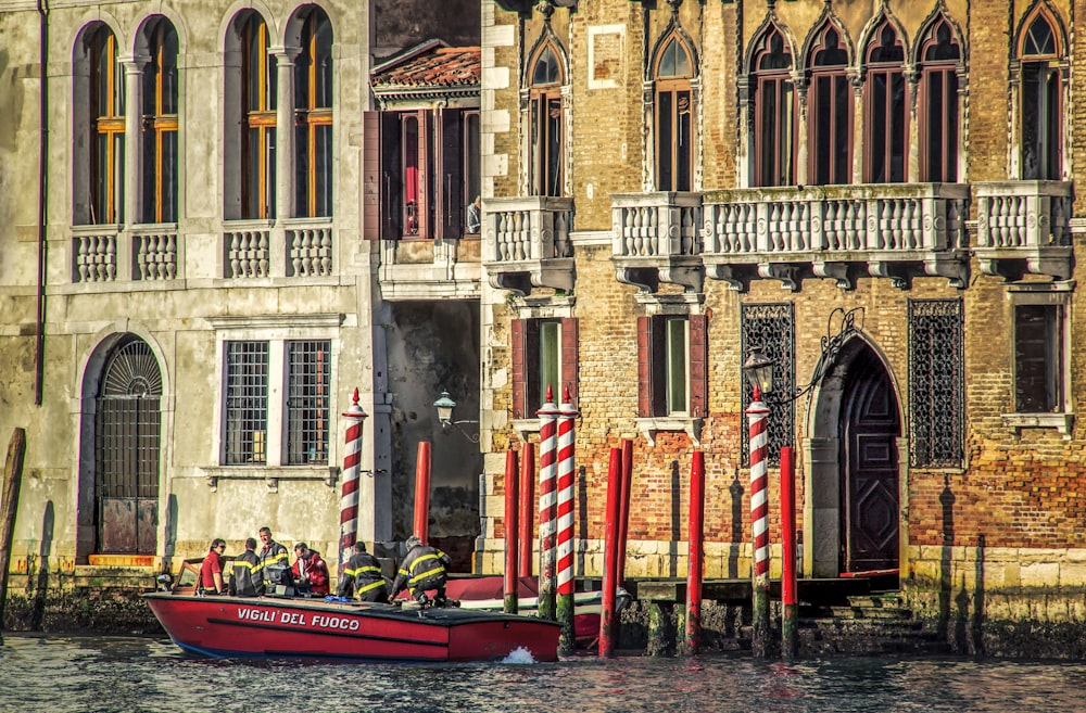 red boat on body of water near brown concrete building during daytime