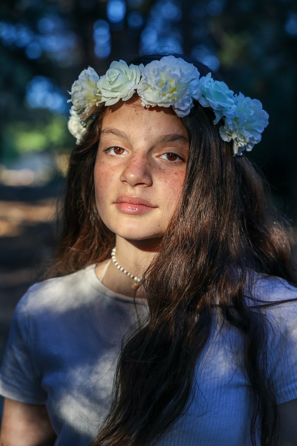 woman in white shirt with blue flower on head