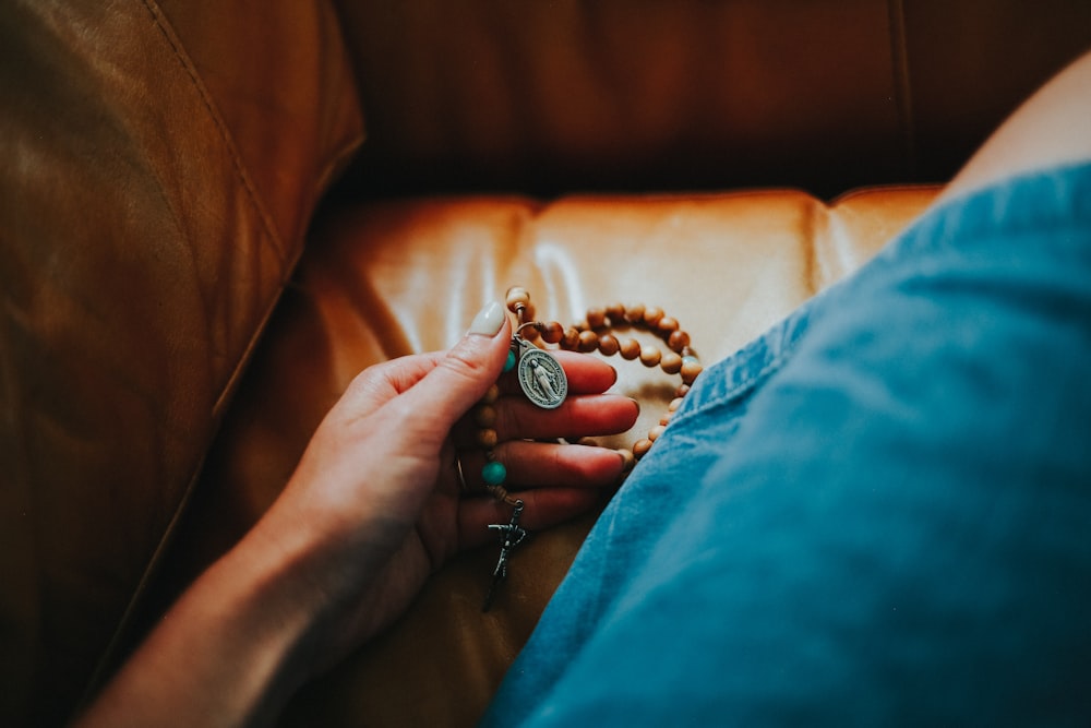 person holding brown and black beaded bracelet