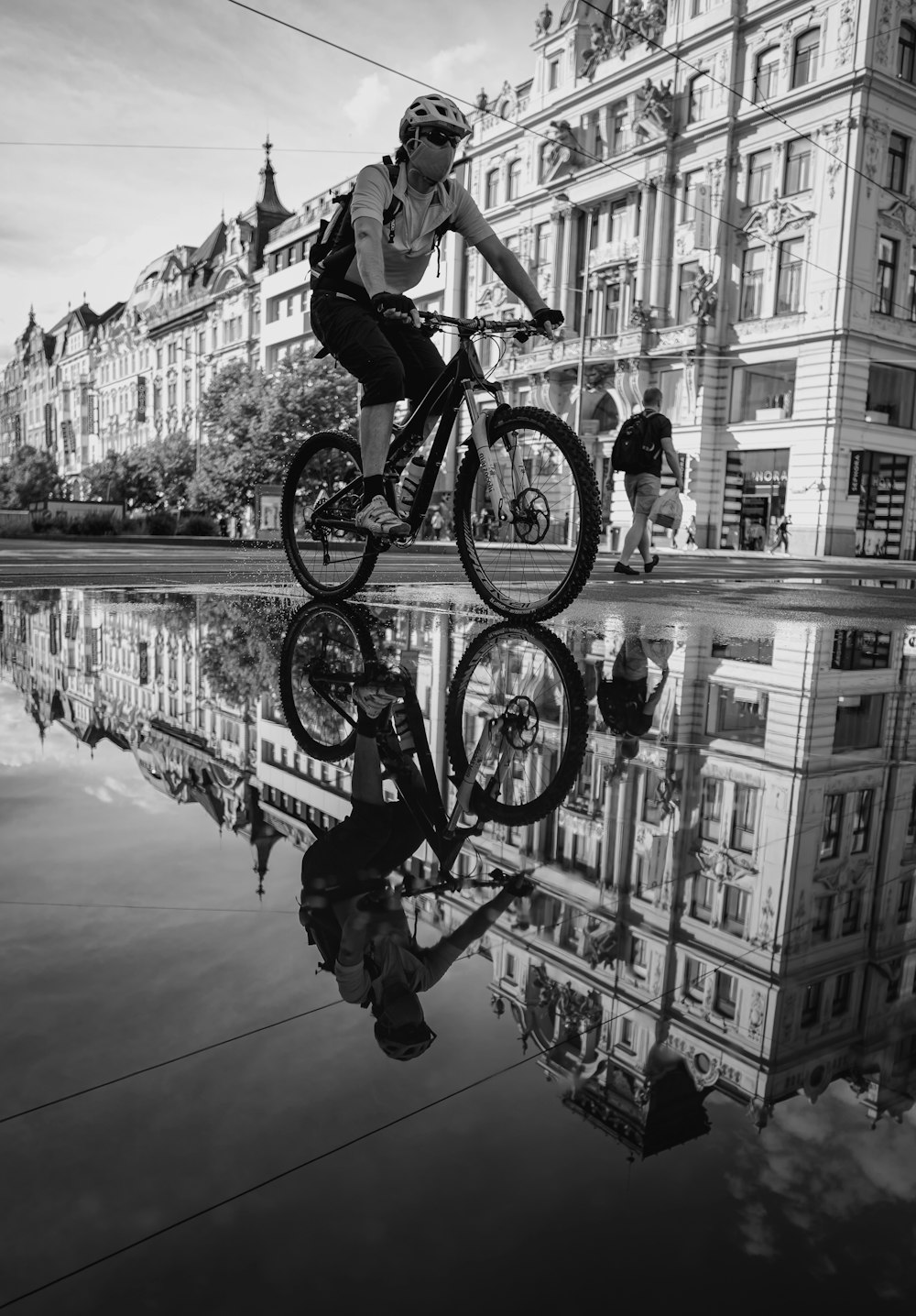 grayscale photo of man riding bicycle