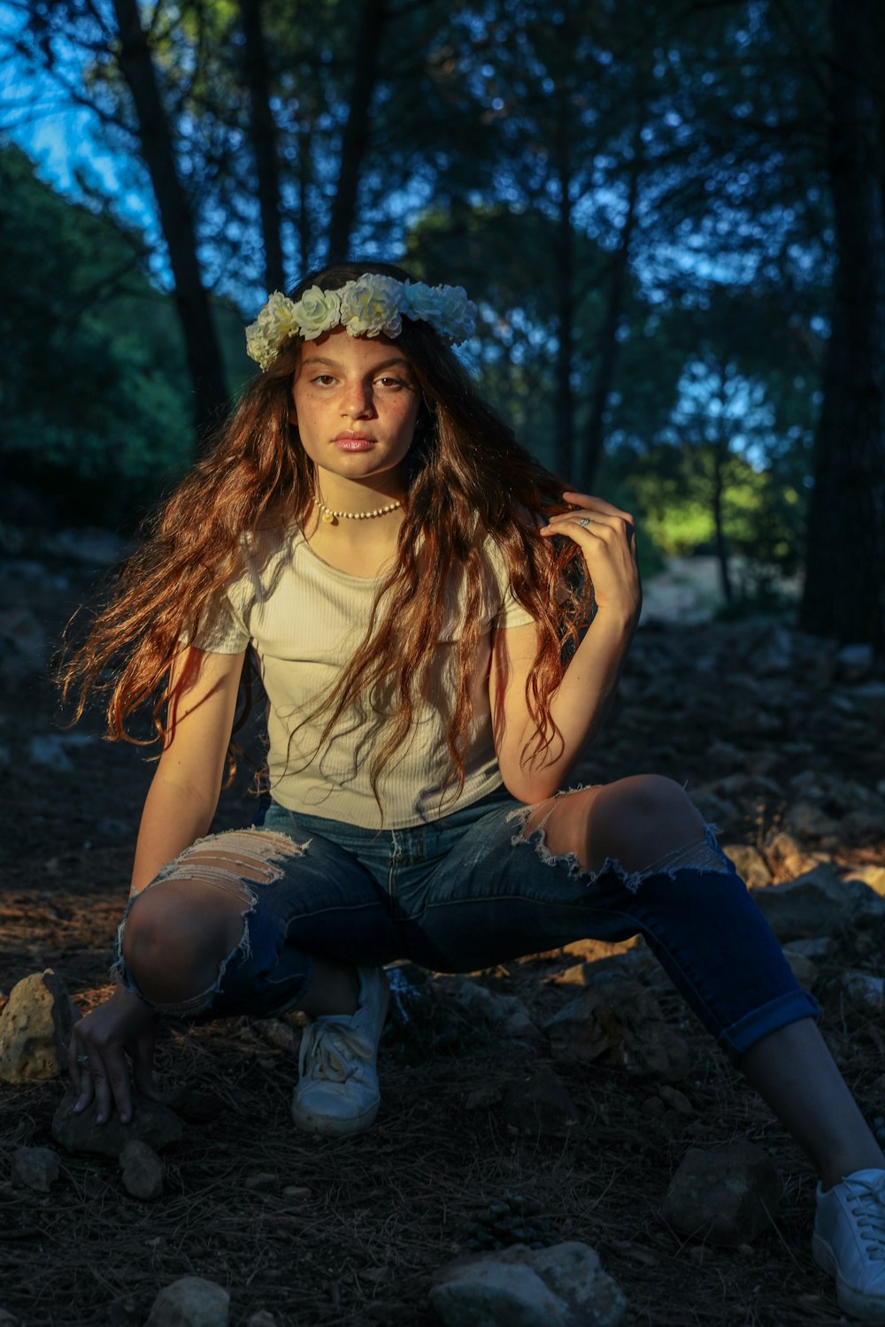 woman in white tank top and blue denim jeans sitting on brown rock