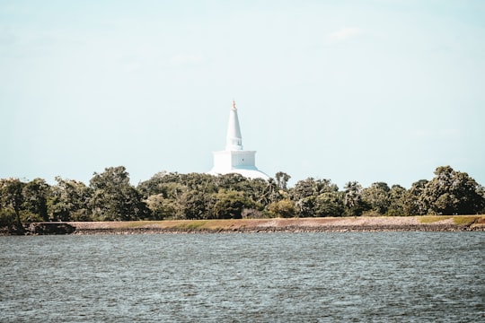 white lighthouse on green grass field near body of water during daytime in Anuradhapura Sri Lanka
