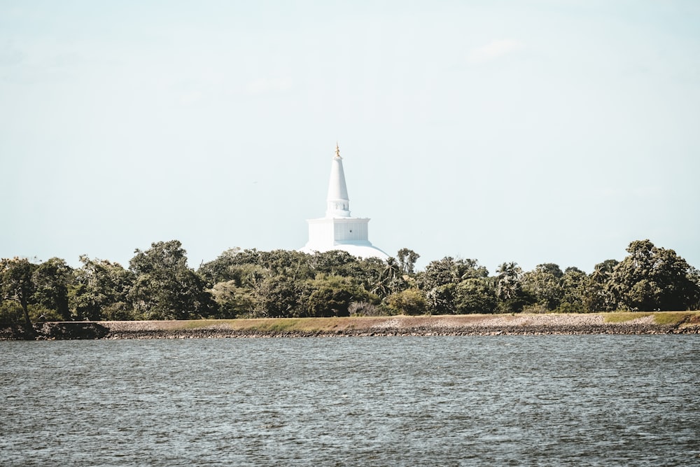 white lighthouse on green grass field near body of water during daytime