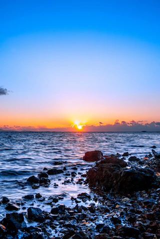 rocky shore with sea waves crashing on shore during sunset