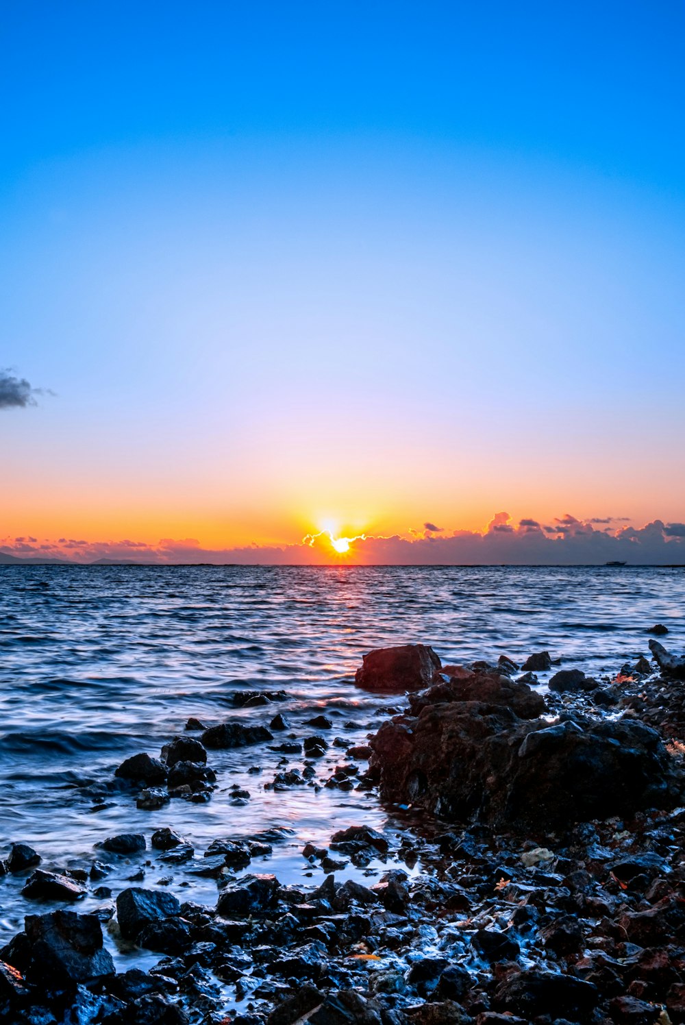 rocky shore with sea waves crashing on shore during sunset