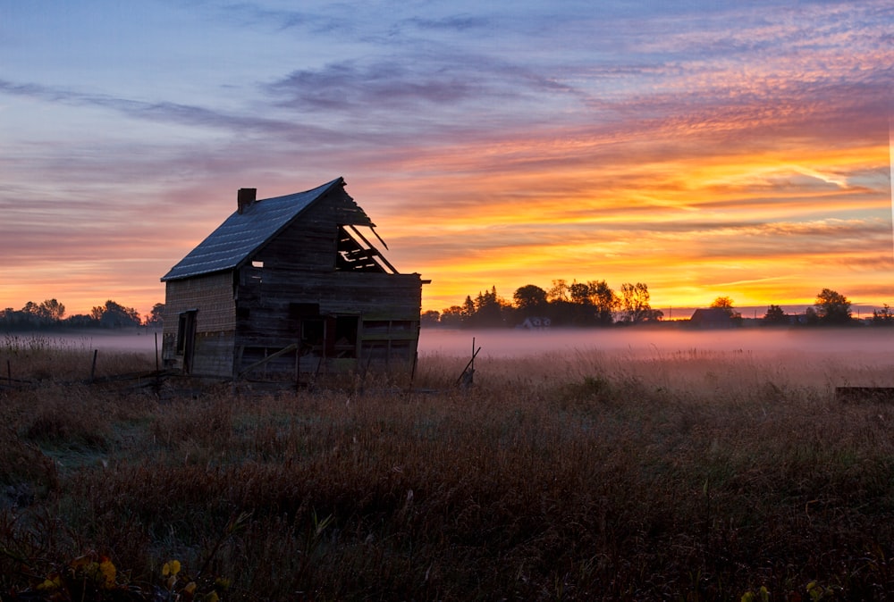 brown wooden house on green grass field during sunset