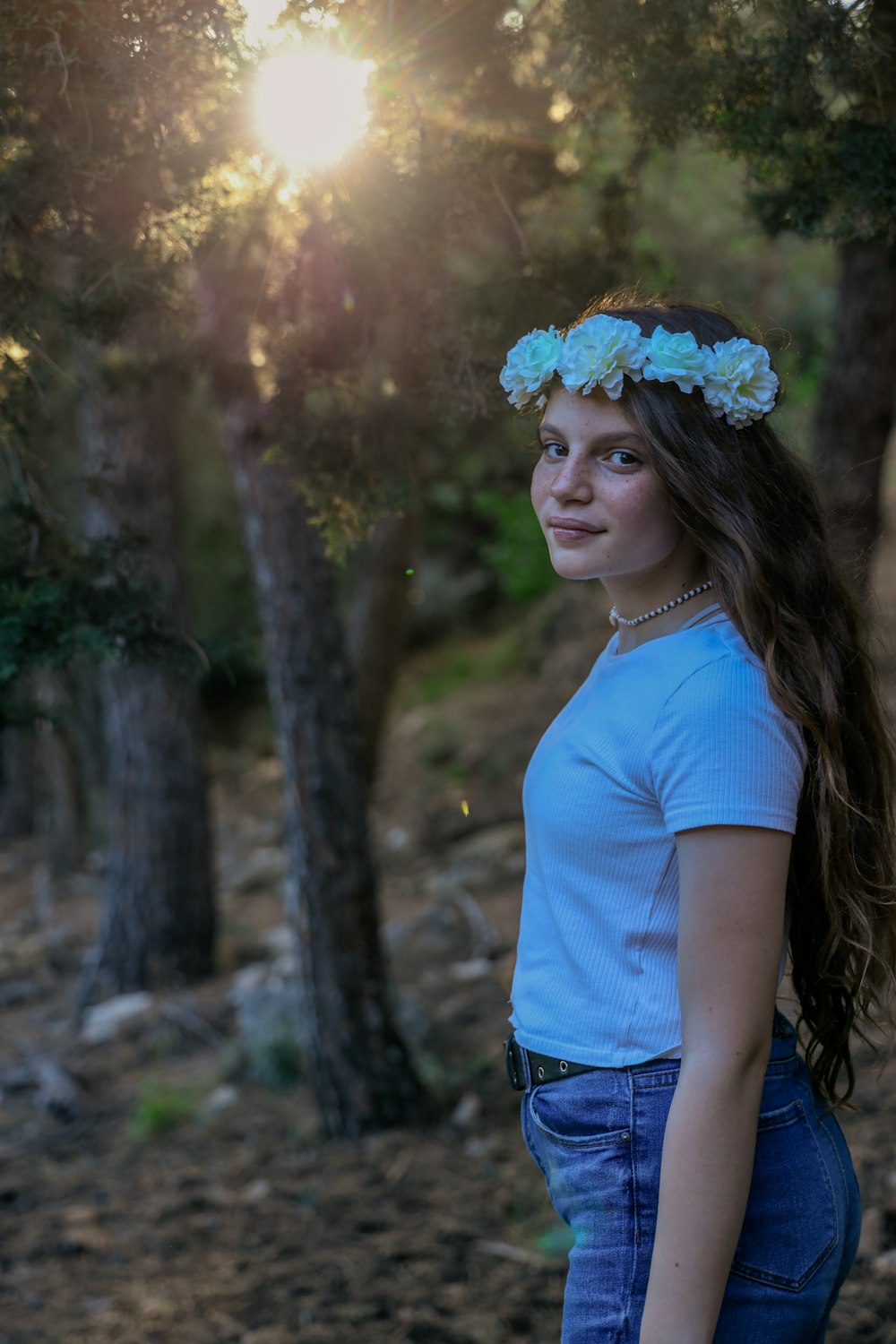 mulher na camiseta azul do pescoço da tripulação e duques margaridos jeans azuis em pé sob a folha marrom