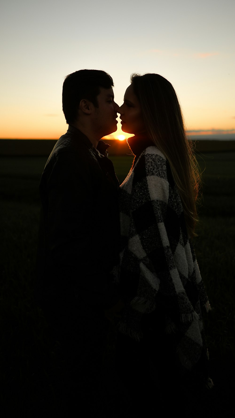 man and woman standing on green grass field during sunset