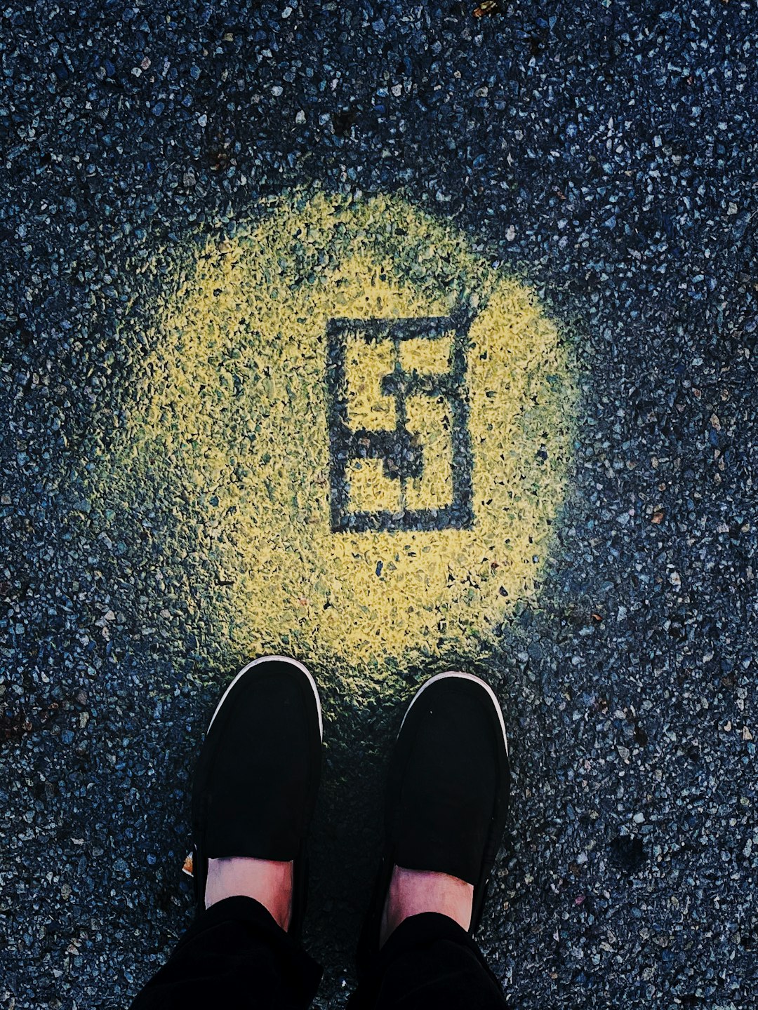 person in black shoes standing on gray concrete floor