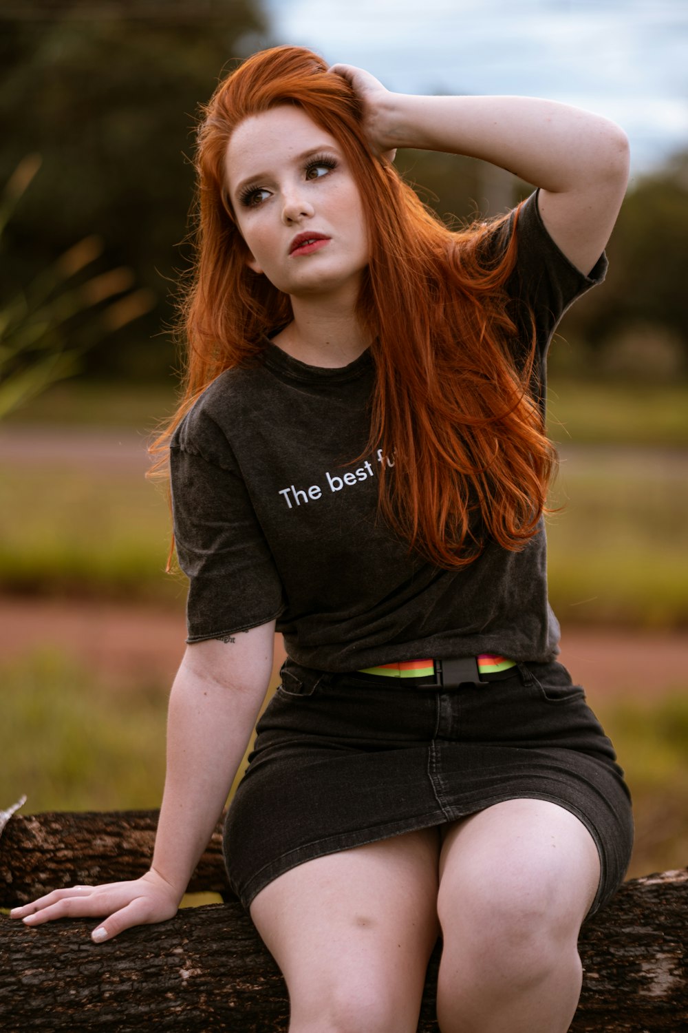 Frau in schwarzem Rundhals-T-Shirt und schwarzen Jeansshorts sitzt auf braunem Felsen während