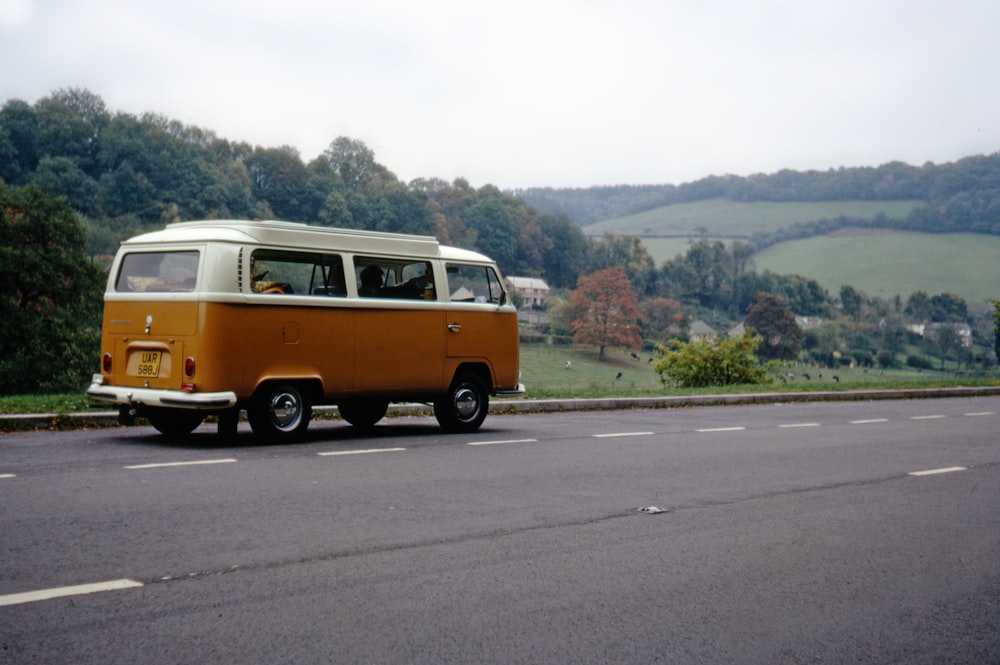Volkswagen T-2 orange et blanc sur route pendant la journée
