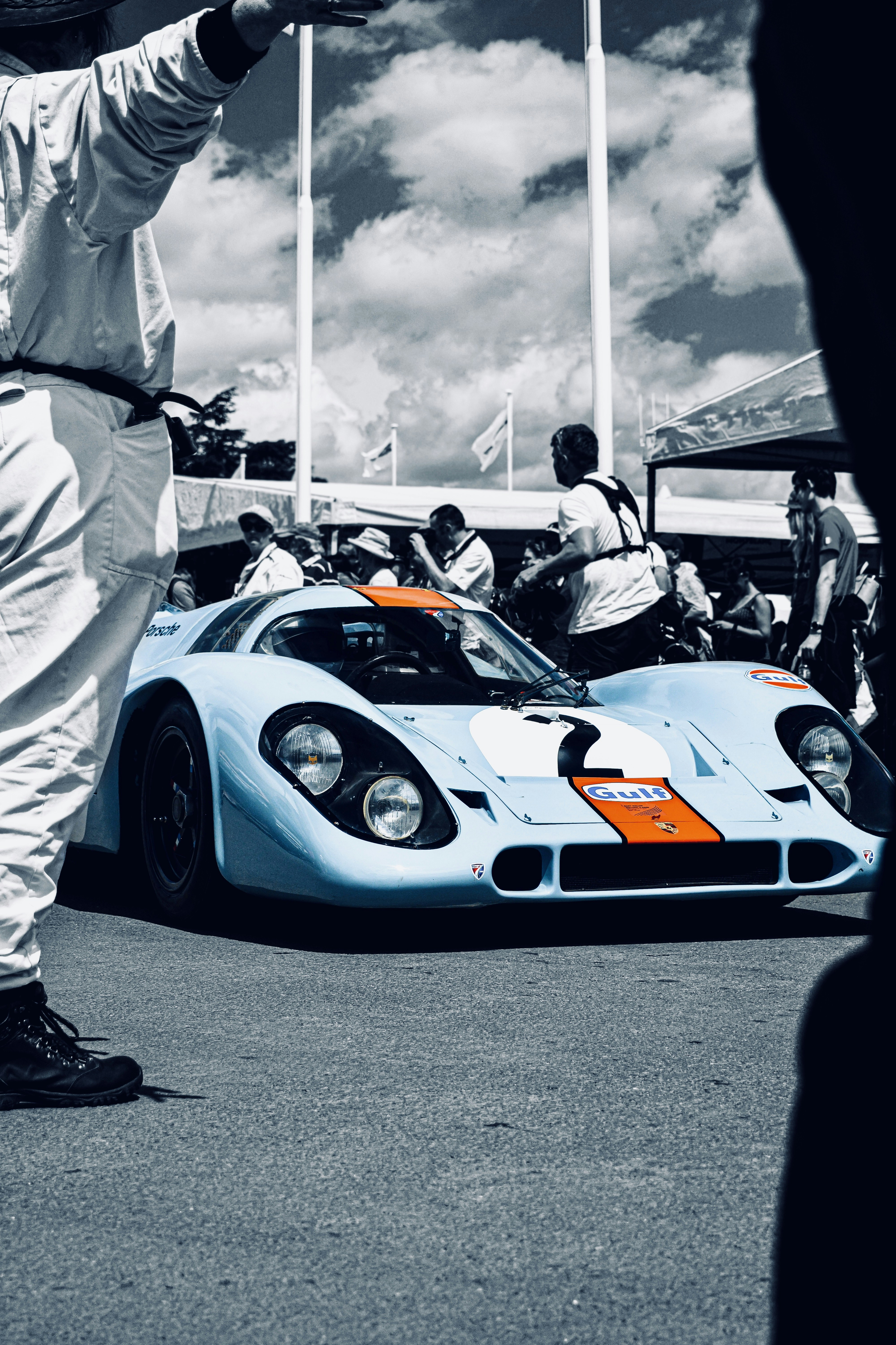 Foto en escala de grises de un hombre vestido de blanco thobe de pie junto a un Lamborghini Aventador blanco