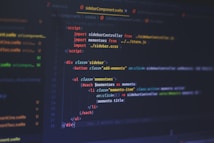 A computer screen displays code written in a text editor. The code is related to web development and includes HTML and JavaScript. The interface shows a dark theme with syntax highlighting, featuring different colors for commands, variables, and elements. Some parts of the screen show filenames and directories on the left.