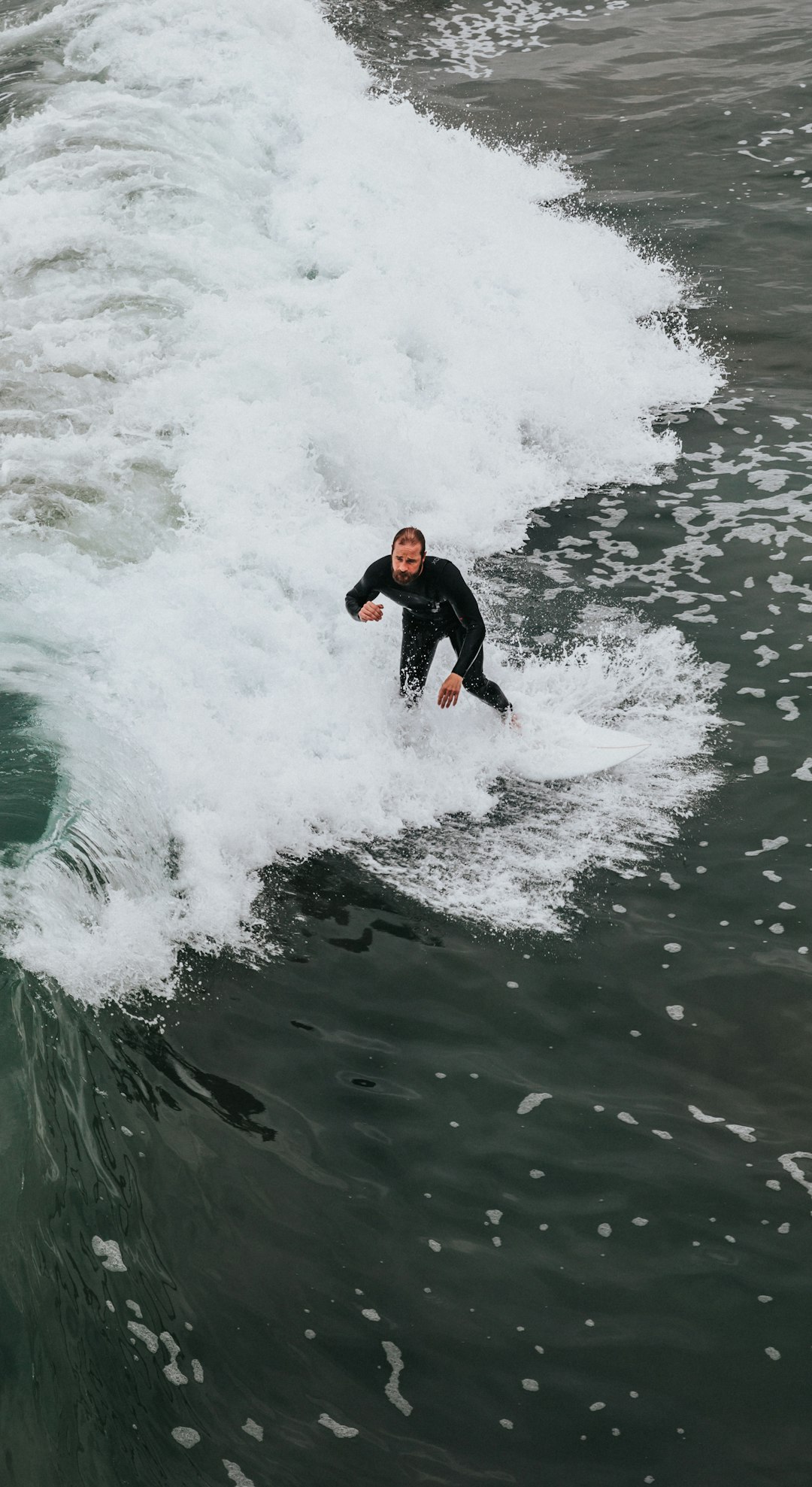 man in black and red wet suit surfing on water during daytime