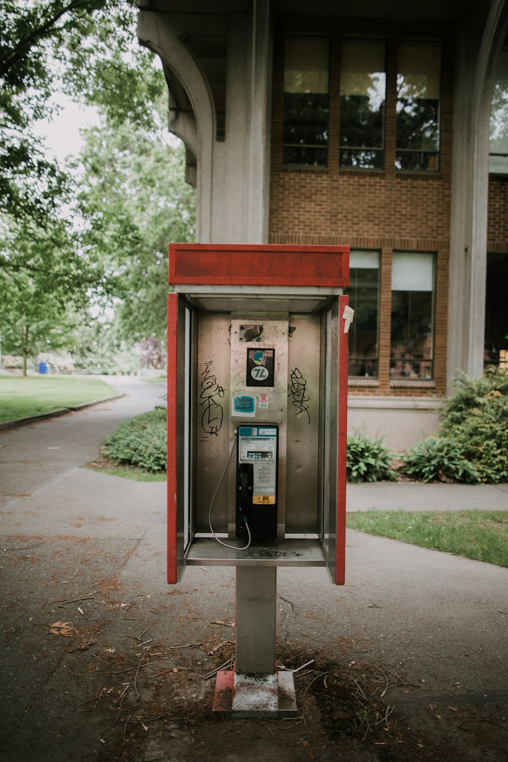 red telephone booth near green trees during daytime