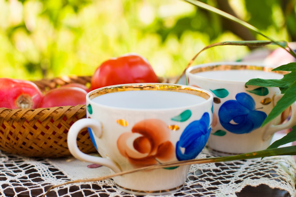 taza de té de cerámica floral blanca, azul y roja sobre platillo de cerámica blanca y azul