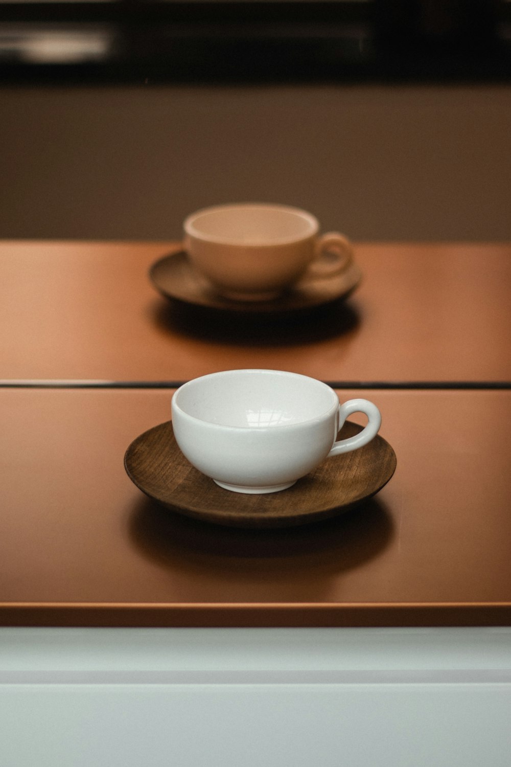 white ceramic teacup on brown wooden saucer
