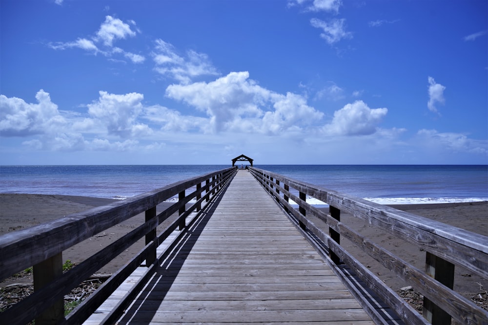 brown wooden dock on blue sea under blue and white cloudy sky during daytime