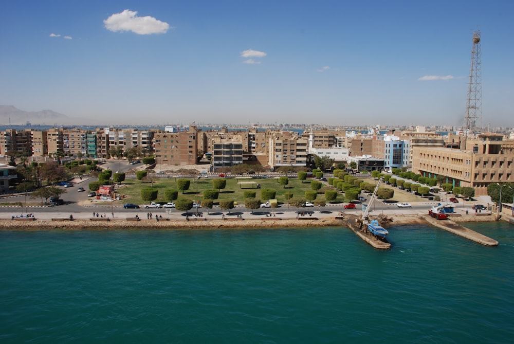 Barca bianca e blu sul mare vicino agli edifici della città sotto il cielo blu durante il giorno