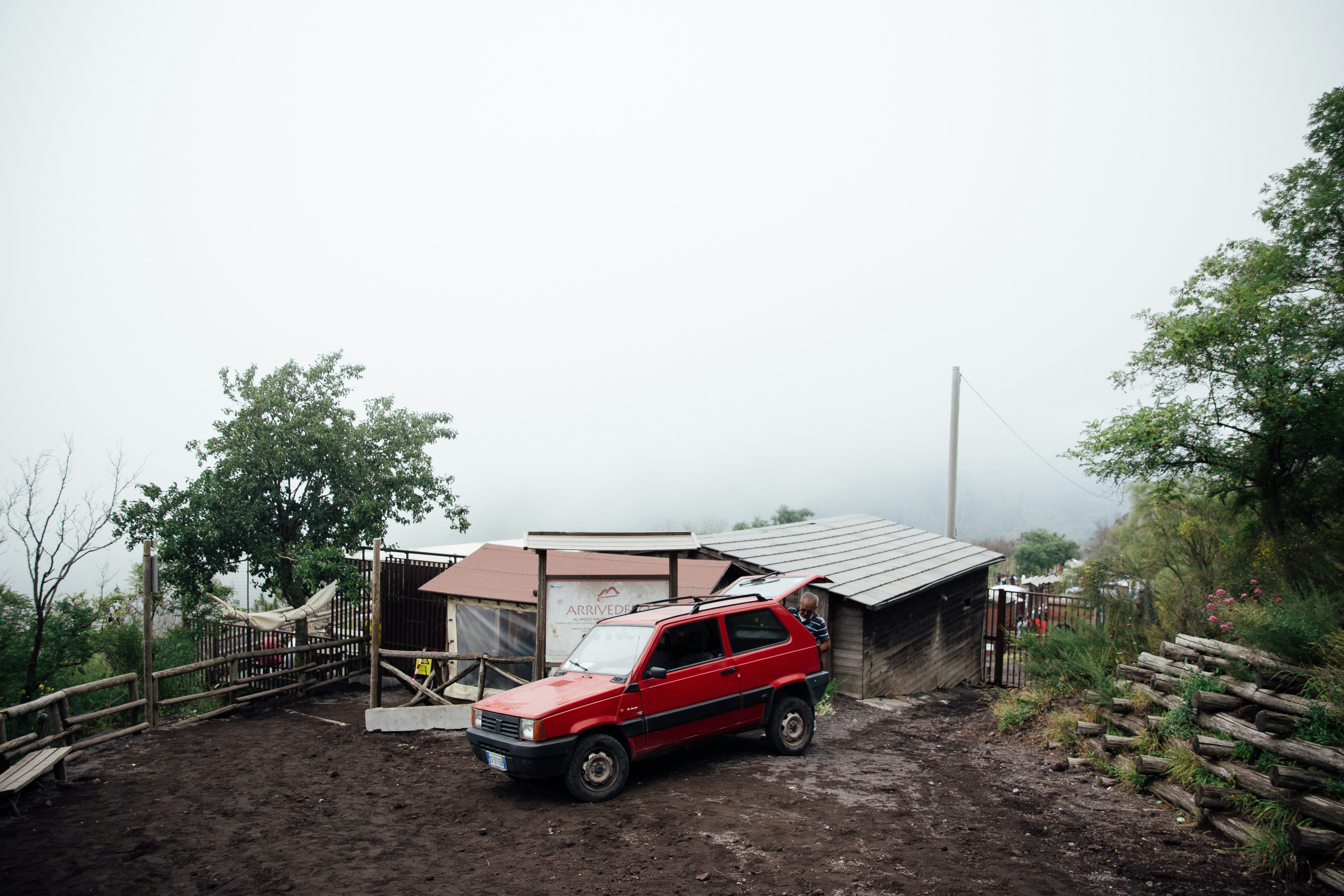 red and blue car parked beside white and blue house during daytime