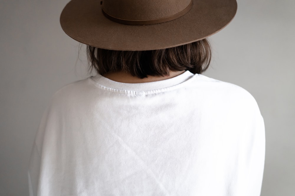 person in white crew neck shirt wearing brown fedora hat